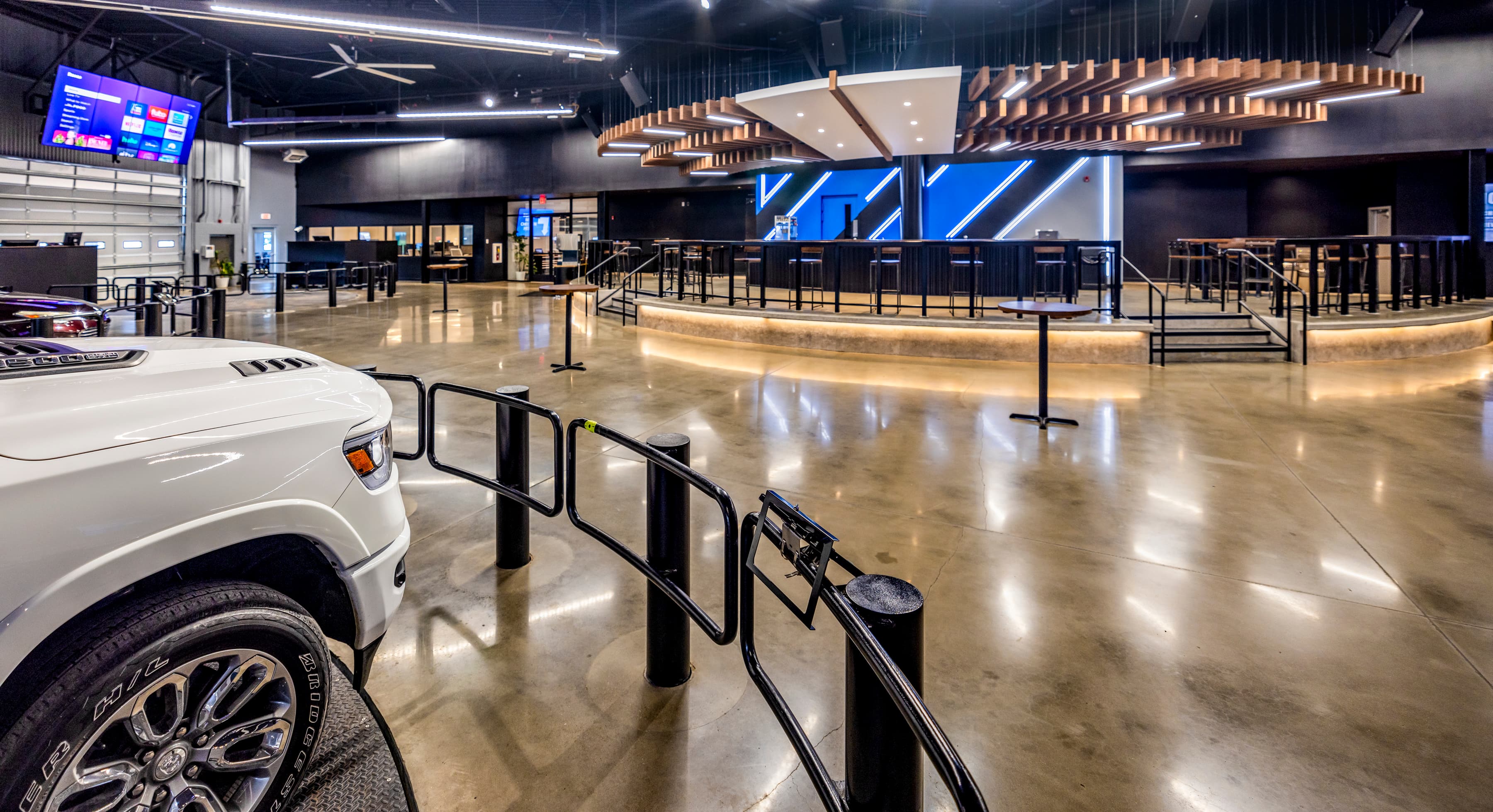The United Auto Exchange auction floor in Memphis: vehicles on the turntable beneath the wood flywheel, diagonal-stripe wall behind the lanes